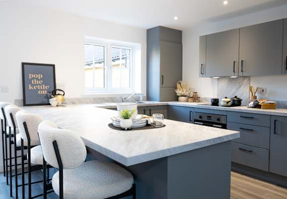 A kitchen with a marble countertop and grey cabinets.