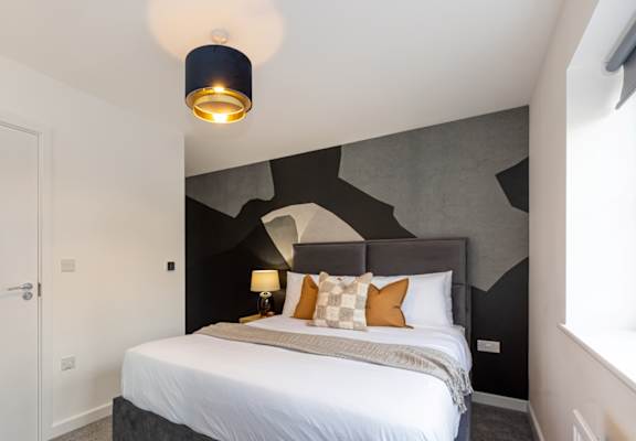 A bedroom with a large bed and a lamp on the side table.