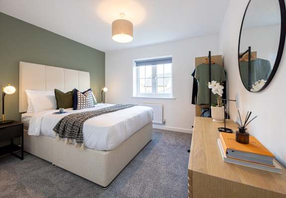 A bedroom with a large bed and a round mirror on the wall.