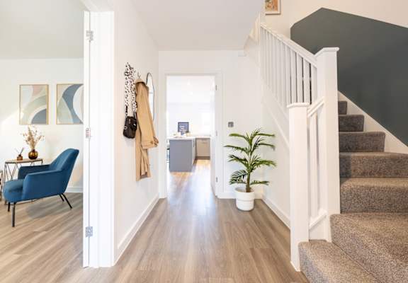 A hallway with a staircase and a blue chair.