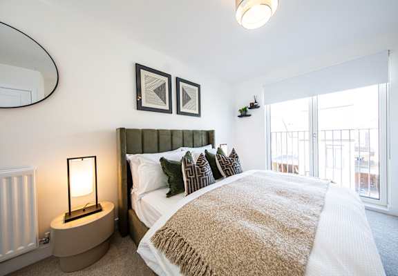 A bedroom with a bed, a lamp, and a mirror.