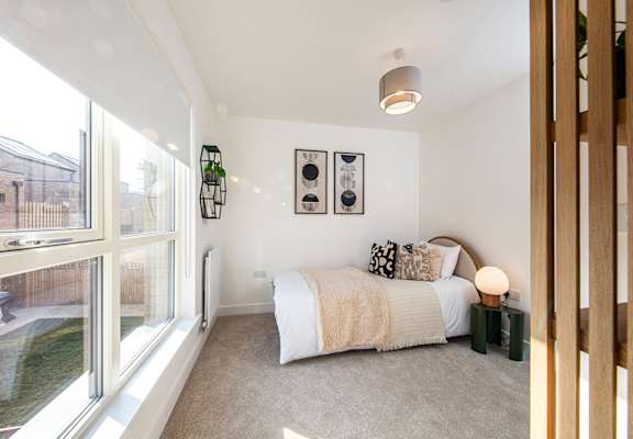 A bedroom with a large bed and a window overlooking a backyard.