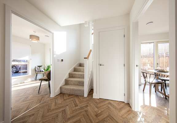 A hallway with a staircase and a white door.