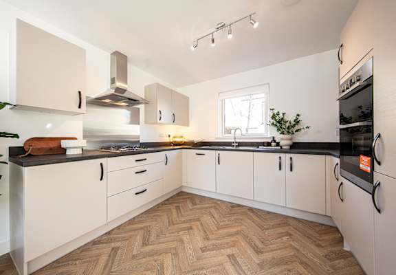 A modern kitchen with white cabinets and a wooden floor.