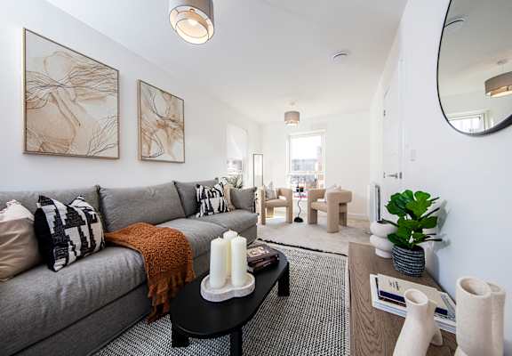 A living room with a grey couch and a large mirror on the wall.