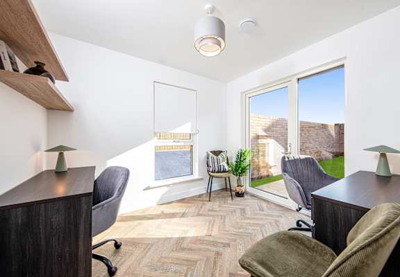 A room with a desk, chairs and a window.