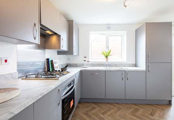 A kitchen with grey cabinets and a white counter top.