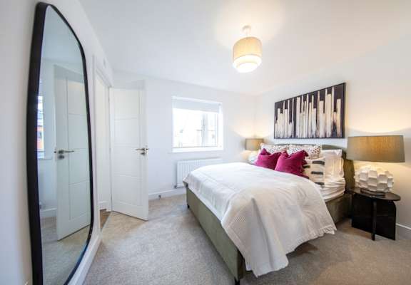 A bedroom with a large bed and a mirror on the wall.