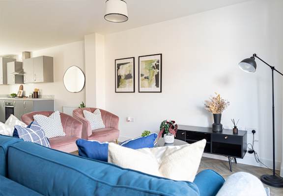 A living room with a blue sofa and a pink chair.