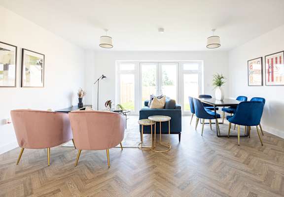 A living room with a pink chair and blue chairs.