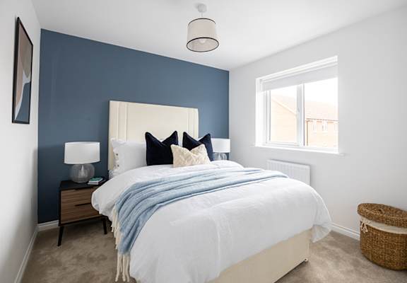 A bedroom with a white bed and a blue blanket.