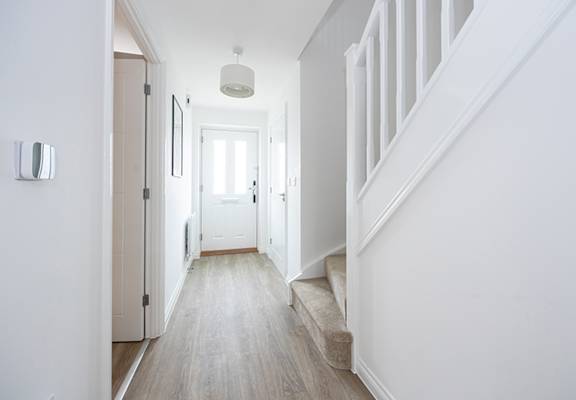 a hallway with white walls and stairs and a white door