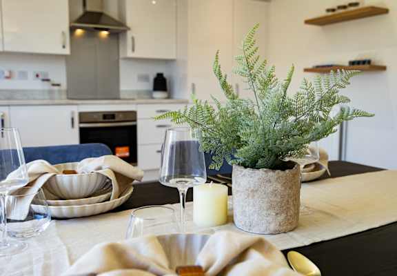 A dining table with a candle and a plant on it.
