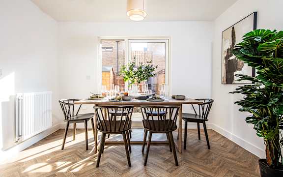 A dining room with a table set for six with a view of the street outside.