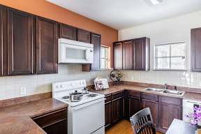 A kitchen with a white stove and wooden cabinets.