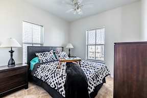 A bedroom with a black and white bedspread and two lamps on either side of the bed.
