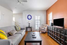 A living room with a grey couch, a black coffee table, a television, and a chair.