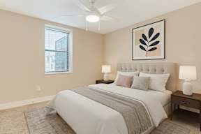 A bedroom with a large bed, two lamps, and a framed picture on the wall.