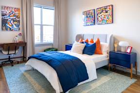 A bedroom with a bed, a nightstand, and two paintings on the wall.