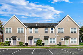 A large two-story apartment building with a parking lot in front.