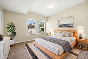 A bedroom with a large bed, a nightstand, and a window.