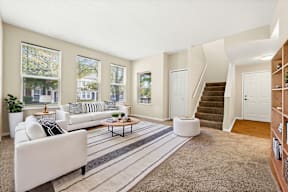 A living room with a white couch and a striped rug.