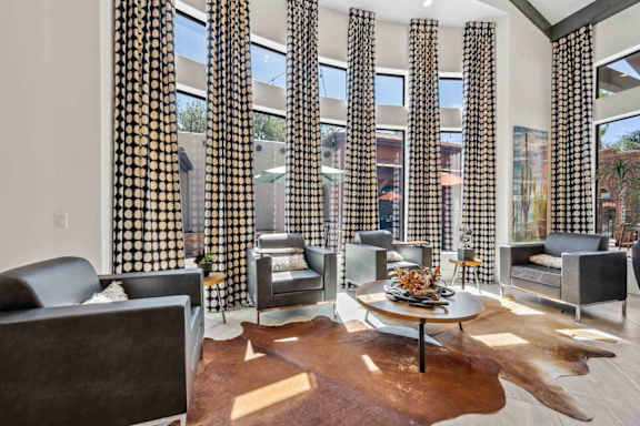 A living room with a cowhide rug and a glass table with a vase of flowers on it.