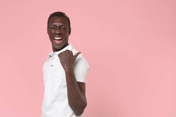 A man in a white shirt is celebrating with a fist pump.