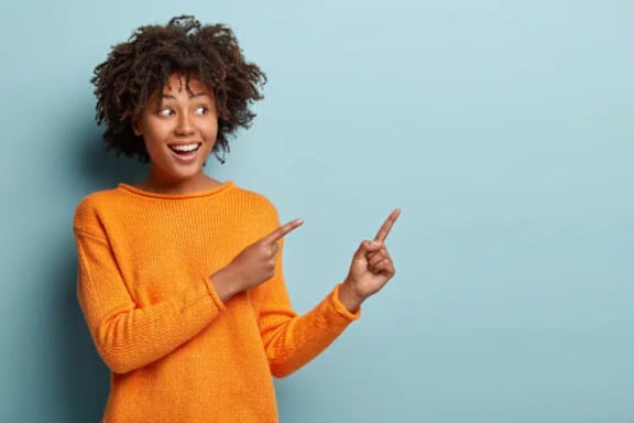 A person in an orange sweater is pointing to the side.