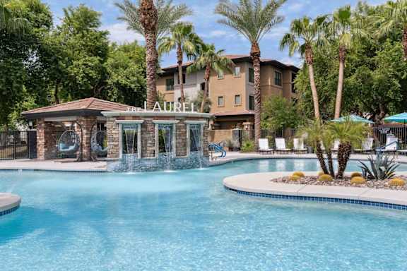 A pool with a waterfall and a building that says Laurel in front of it at The Laurel Apartments, Chandler