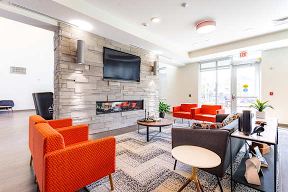 A living room with a stone fireplace and a flat screen TV mounted above it.