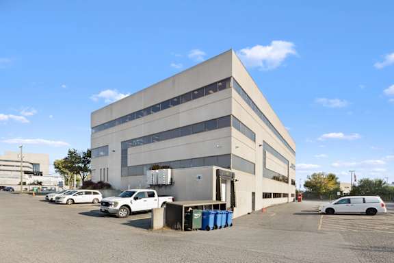 A large grey building with a parking lot in front.