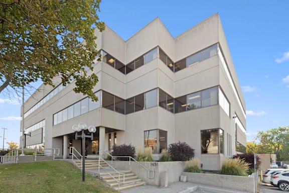 A modern building with a beige facade and large windows.