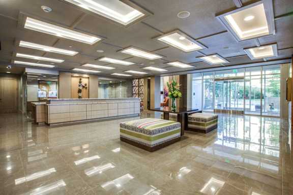 A spacious waiting area with a reception desk and two seating areas. at Uptown by Onni Apartments, Apartments, Dallas, TX
