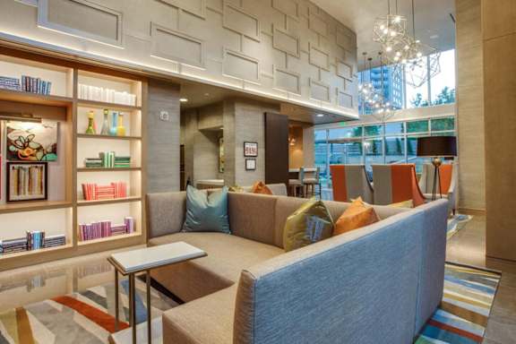 A living room with a couch, a coffee table, and a bookshelf. at Uptown by Onni Apartments, Apartments, Dallas, TX