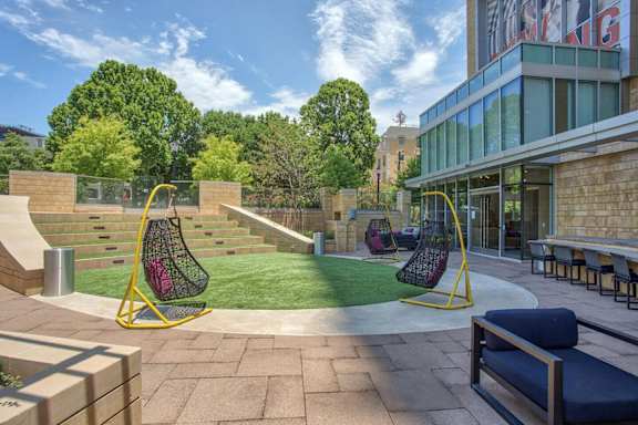 A playground with a swing set and a slide. at Uptown by Onni Apartments, Apartments, Dallas, TX