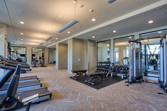 A gym with treadmills, weights, and exercise equipment. at Uptown by Onni Apartments, Apartments, Dallas, TX