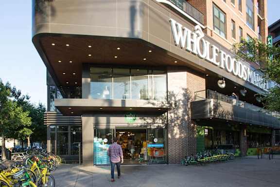 A Whole Foods Market store with a man standing in front. at Uptown by Onni Apartments, Apartments, Dallas, TX