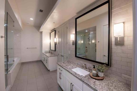 A bathroom with a large mirror and a sink. at Uptown by Onni Apartments, Apartments, Dallas, TX