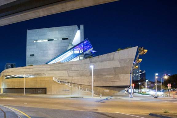 A modern building with a unique design is illuminated at night. at Uptown by Onni Apartments, Apartments, Dallas, TX