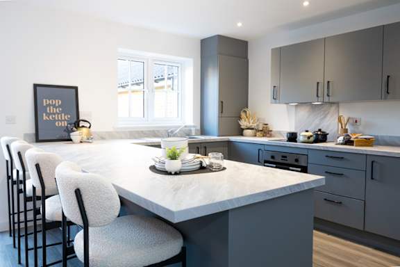 A kitchen with a marble countertop and grey cabinets.