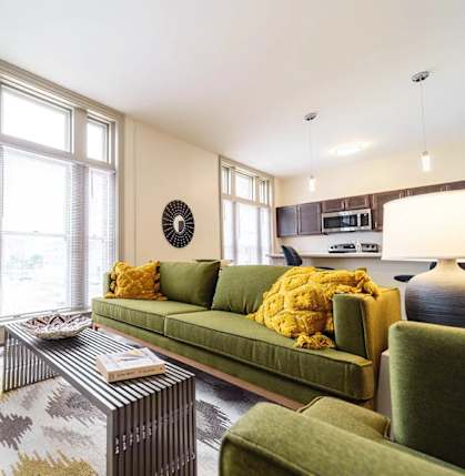 A living room with a green couch, a red chair, and a patterned rug.