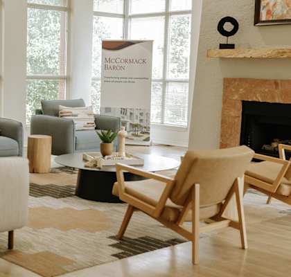 A living room with a fireplace and a banner that says "McCormack Baron".