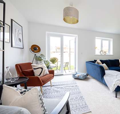 A living room with a blue couch and a white rug.