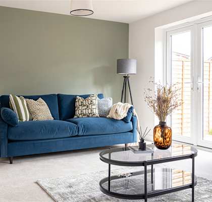 A blue couch with a black metal coffee table in front of it.