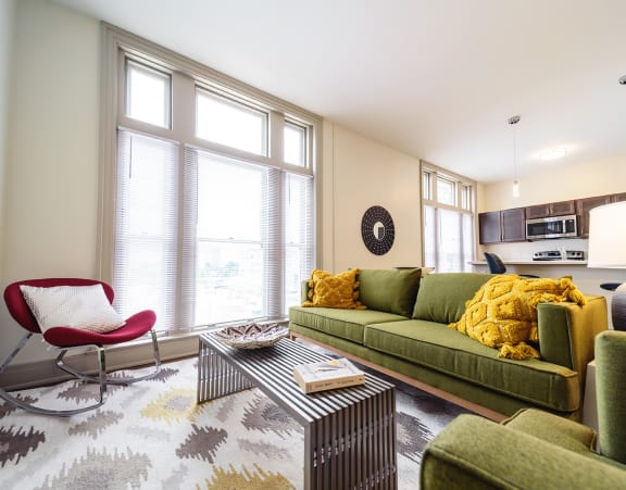 a living room with a couch and a dining table and a refrigerator surrounded by cabinets