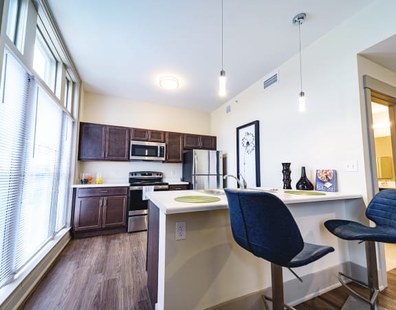 a living room with a couch and a dining table and a refrigerator surrounded by cabinets