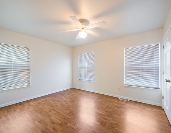 a bedroom at Beecher Terrace apartments with two windows and a bed with white sheets and pillows