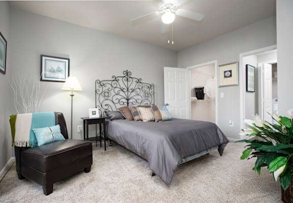 a bedroom with a bed and a chair and a ceiling fan