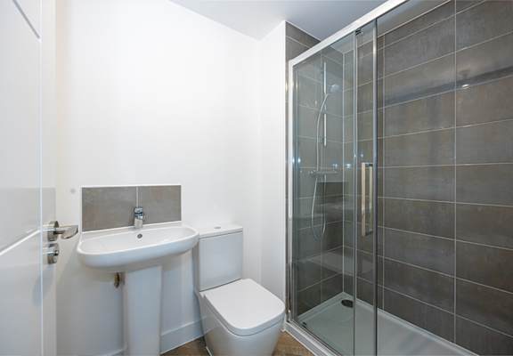 A white sink and toilet in a bathroom with a glass shower door.